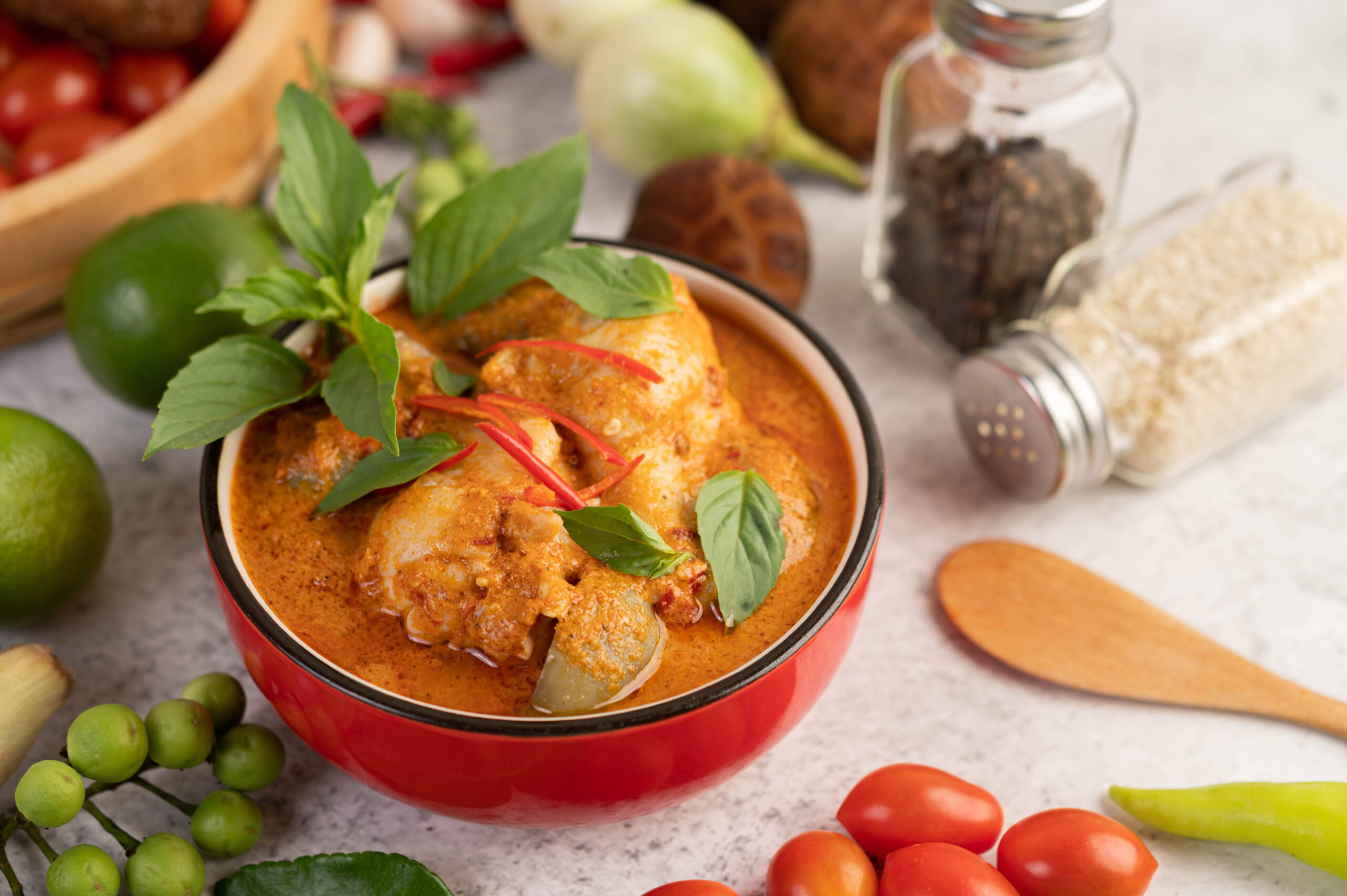 Chicken red curry in a black bowl, chilli, tomato, galangal, shiitake mushroom and eggplant